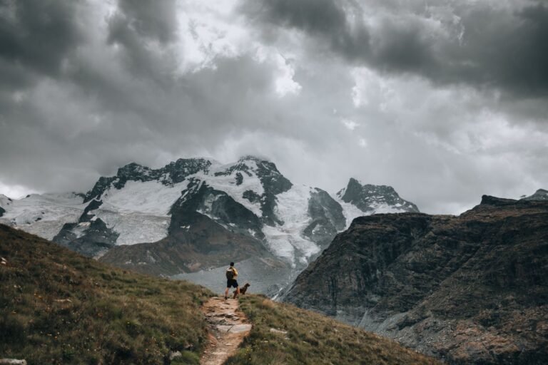 Hiker and dog walking along a mountain trail